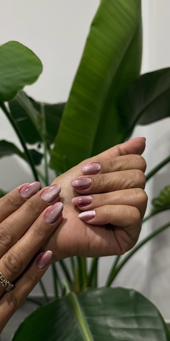 Monstera yaprakları önünde doğal nude tırnaklar